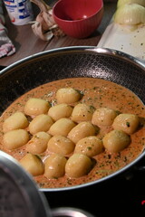 color photo of a dish of potato gnocchi sprinkled with parmesan, in a pepper sauce, with herbs, traditional homemade tasty food, close up view