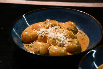close up view of food background, potato gnocchi with pepper cream sauce, grated parmesan cheese and herbs, close up view of served food