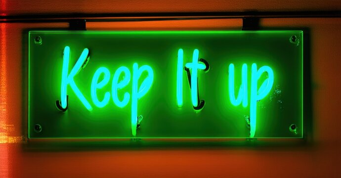 Glowing neon sign displaying Keep It Up in bold vibrant green letters, mounted on a dark background, radiating motivation, encouragement, and perseverance to continue progressing