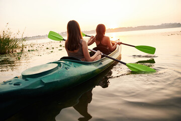 Together on the same boat. Women friends are on sup board on the lake
