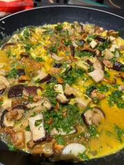  Omelette aux champignons en cuisson dans une poêle, garnie de persil frais.