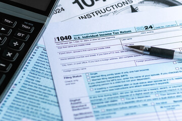 Blank color print paper Form 1040 U.S. Individual Income Tax Return 2024. With a black ball pen and calculator. Taxation, tax season 2025, tax payment, regulatory filing, personal finance concept