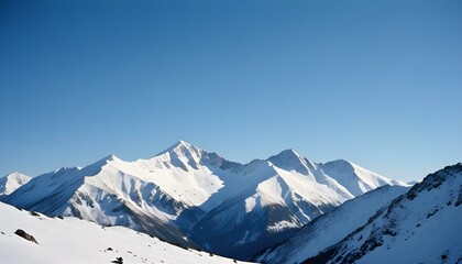 Obraz premium Snow covered mountain peaks under clear blue sky with sharp ridges and shadows