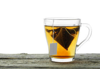 Tea bag in glass cup with hot drink on wooden table against white background. Space for text