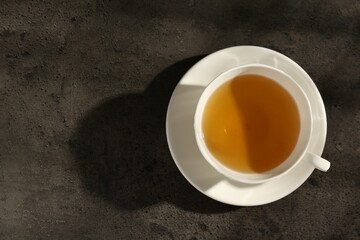 Refreshing green tea in cup on dark textured table, top view. Space for text
