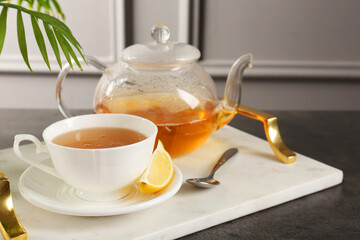 Refreshing green tea, spoon and slice of lemon on dark textured table