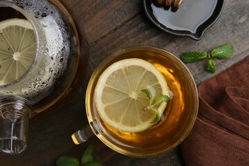 Tasty mint tea in cup, lemon and fresh leaves on wooden table, flat lay
