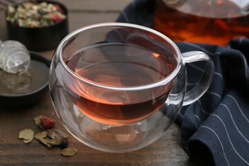 Delicious herbal tea with honey and dry leaves on wooden table, closeup