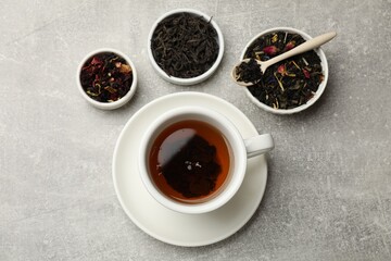 Aromatic tea and dried leaves on grey table, flat lay