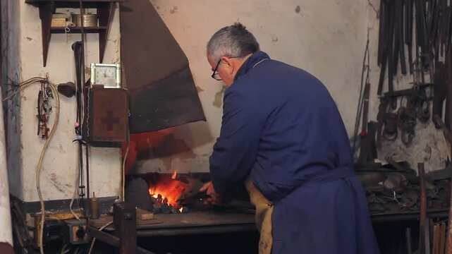 Blacksmith at work, coal fire melts iron in a furnace for further processing with a hammer on an anvil in smithy, close-up. Traditional manual production in the forge, blacksmith workshop