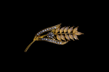 A gold leaves-shaped brooch displayed on black background