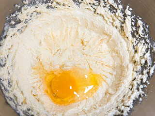 Beating butter, sugar and eggs in a grey metal bowl. The process of making cake and cookies by mixing butter, eggs and sugar.