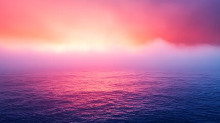 Fototapeta premium Colorful sunrise over a misty ocean creating an ethereal glow