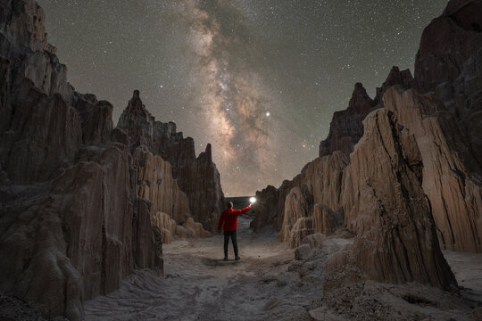 Man surrounded by creepy jagged rock formations under the milky way galaxy in Nevada 