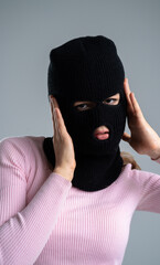 Woman in Black Balaclava posing in the studio against a gray background