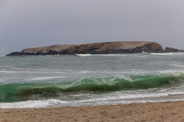 beach with waves of more calm with a background of blue sky seagulls and a summer island 