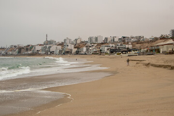 sandy beach with waves with buildings in the background in punta hermosa Perú 