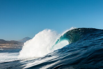 olas rompiendo en una playa con un bonito paisaje volcánico