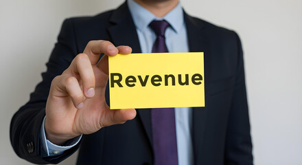 Businessman is holding a card on which is written revenue, Business, Corporate, Office, Teamwork, Finance, Technology, Meeting, Success, Marketing, Strategy.