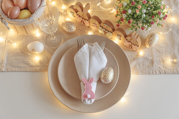 Festive Easter table setting with Easter bunny made from napkin decorated lights. Easter...