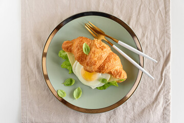 Croissant toast with lettuce, cheese and fried egg on white table. Top view