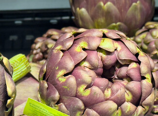Obraz premium Close-up of fresh purple artichokes stacked at the market