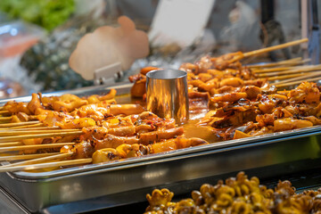 A variety of barbecue meat and seafood skewers with sauce are being sold at the food stall.