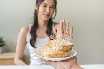 Gluten allergy, asian young woman hand push out, refusing to eat white bread slice on plate in...