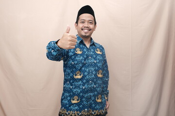 Handsome Indonesian government worker man wearing batik korpri uniform smiling and giving thumb up...