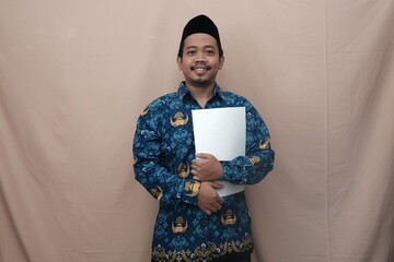 Indonesian man as government worker or civil servant with Korpri batik uniform bringing document...