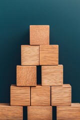 Obraz premium Wooden blocks arranged in a stylish pyramid formation against a teal background, perfect for educational themes and creative designs.