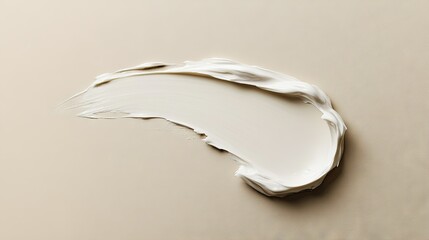 A soft white beauty cream stain on a beige background, captured from above to highlight its luxurious texture.