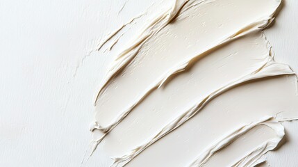 A top view of a white beauty cream stain, gently spread on a white surface, emphasizing its silky smoothness.