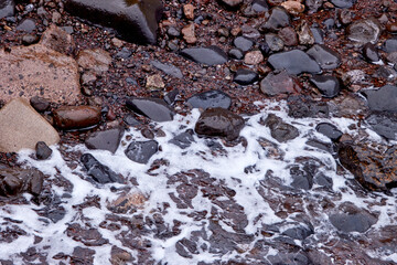 Wellenbewegung auf Steinen – Natürliche Struktur. Dynamische Nahaufnahme von Wasser, das über...