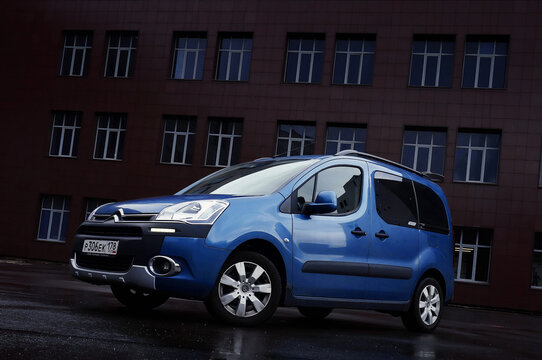 Blue passenger minivan Citro&euml;n Berlingo B9 parked on a rainy day. Three-quarter front view and off-level horizon. Large dark-brown office buildin in the background. 22.08.14 S-Petersburg, Russia.