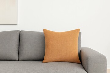 Minimalist interior design featuring a gray sofa with a textured orange cushion, evoking a cozy and modern atmosphere perfect for contemporary living spaces