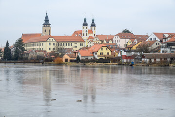 Obraz premium View of Historic old town of Telc, Unesco World Heritage Site, across frozen Ulicky rybnik pond in winter in Czech Republic