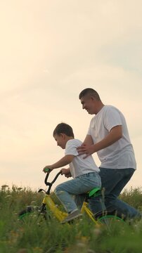 man father teaches boy son ride bike, schoolboy boy playing happily dad park, father running after bike child green meadow, happy family outdoors, children dream, adrenaline fast cycling, childhood