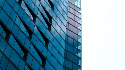 A modern glass building displays a rhythmic, angular pattern on its façade, reflecting muted sky...