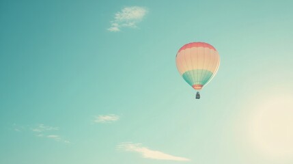 Naklejka premium Hot Air Balloon Floating in a Pale Blue Sky with Soft Clouds.