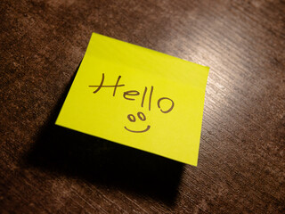 yellow sticky note with friendly greeting on a table