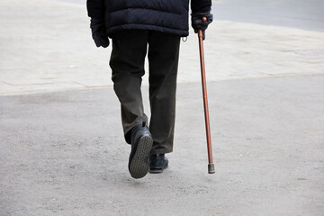 Man walking with a cane down the street. Concept of old age, limping person