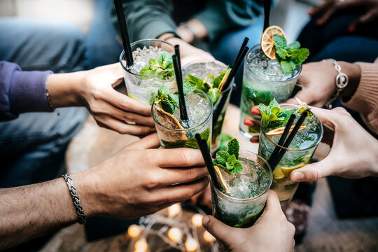 Happy friends group cheering mojito glass drinks at cocktail bar restaurant - Young people having fun at party time drinking cocktails on happy hour at pub - Food, beverage life style concept