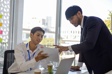 Two men shake hands in a business setting. One man is wearing a tie. Scene is professional and friendly
