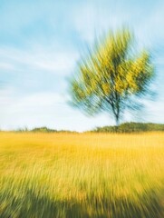 Naklejka premium Abstract Impressionist Landscape with Tree and Golden Field, Motion Blur Effect.