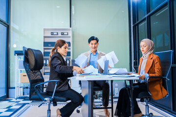 A middle-aged Asian man and Muslim woman in hijab engage in a tense business meeting. proposals,...