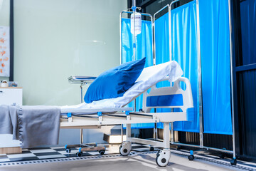 An empty medical bed sits in a glass hospital room, bathed in daylight. Equipped with adjustable features, it awaits the next patient, essential medical equipment for emergency and critical care.
