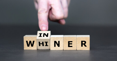 Hand turns cube and changes the word whiner to winner.