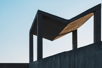 Minimalist urban canopy with strong angular shadows on a concrete wall. The clean architectural composition and geometric design enhance the modern cityscape.