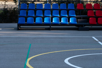 Empty sports court with colorful stadium seating, emphasizing strong geometric patterns and contrast. The bold color palette enhances the modern architectural design.